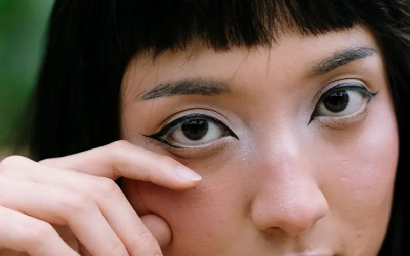 A detailed close-up of a woman's face highlighting bold makeup and intense eye expression.