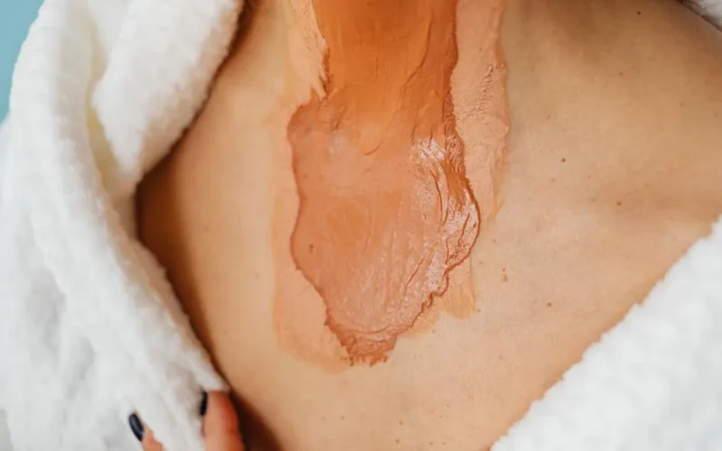 Detailed close-up of a woman applying foundation on her neck with various skin tones.