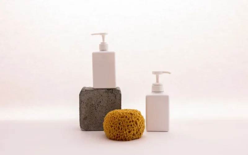 Simple arrangement of skincare dispensers and sponge against a white background, creating a minimalist look.