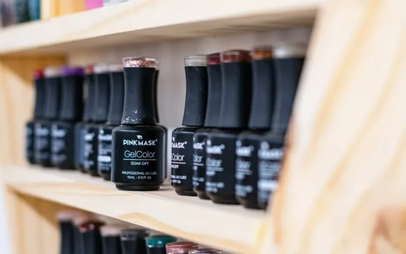 A vibrant collection of gel nail polish bottles neatly organized on a wooden shelf.