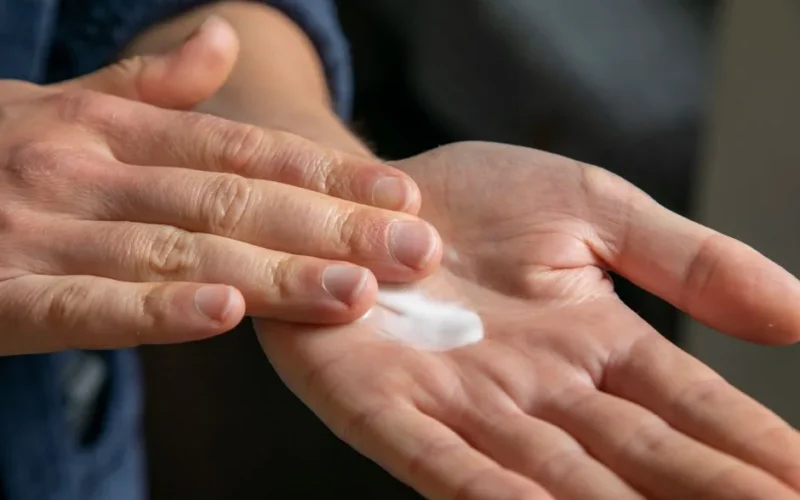 Detailed view of hands applying cream for skincare use.