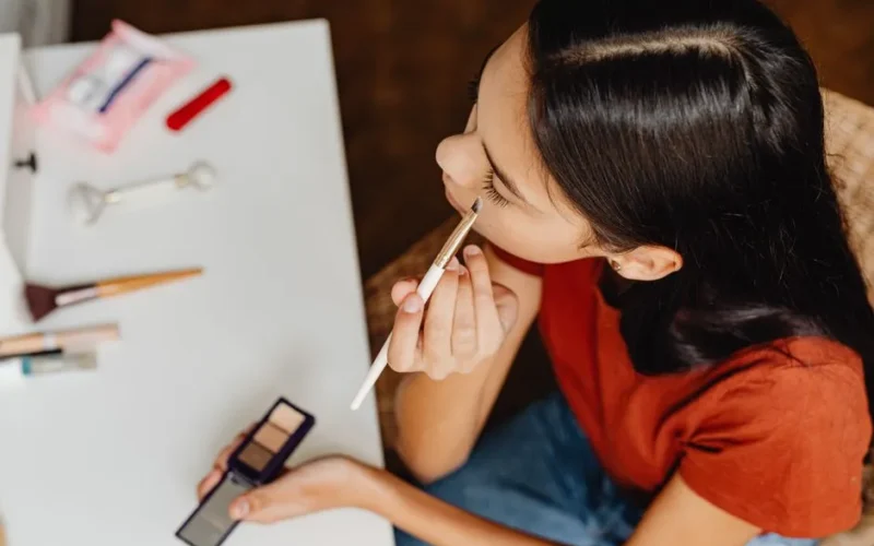 Teenage girl applying eyeshadow at home as part of her beauty routine.