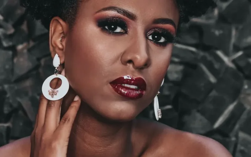 Captivating close-up portrait of a beautiful woman with striking makeup, red lipstick, and stylish earrings.