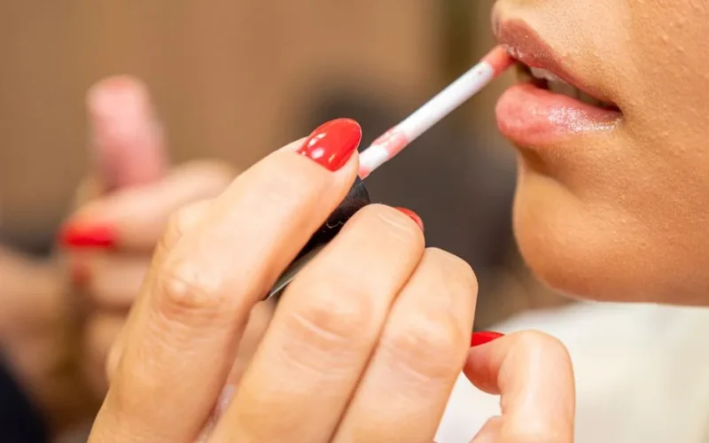 Detail shot of a woman's lips being carefully painted with lipstick.