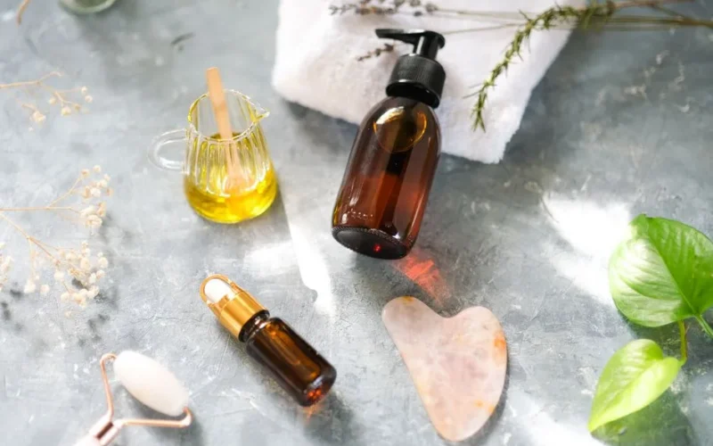 Stylish flat lay showcasing beauty products with oils, jade roller, and leaves for a natural skincare routine.