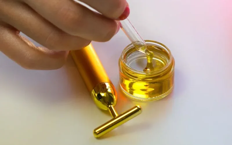 Close-up of a hand handling a serum dropper with massage tool showcasing luxury skincare routines.