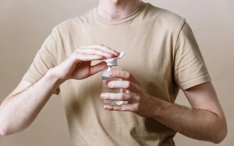 Adult male opening a bottle of micellar water, representing a skincare routine.