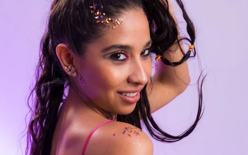 Portrait of a woman with glitter and bold makeup in a studio setting.