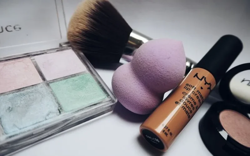 A flat lay showcasing various makeup essentials including brushes, sponges, and cosmetics.