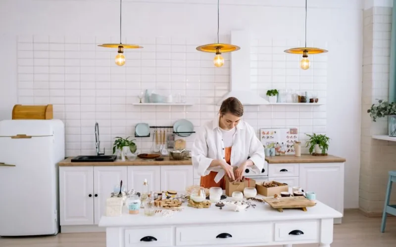 Woman creating handmade crafts in a cozy, modern kitchen setting with warm lighting.