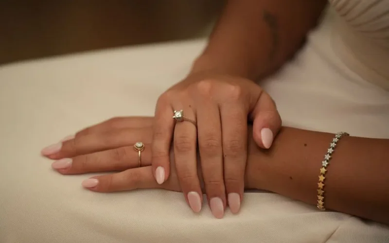 A close-up photo showcasing elegant manicured hands adorned with rings and a bracelet.