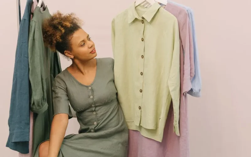 Woman in a boutique admiring beautiful linen clothes on hangers.