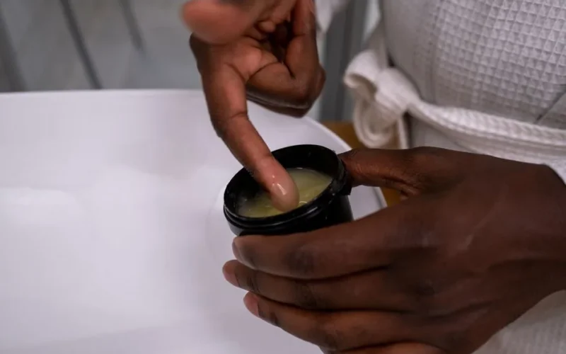Detail of hands applying moisturizing cream from a container. Ideal for skincare and beauty concepts.