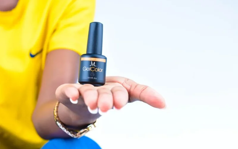 A close-up image of a hand holding a gel nail polish bottle, showcasing beauty and wellness.
