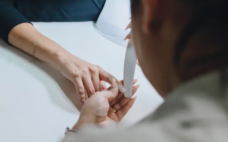 Close-up of a manicurist filing nails during a professional manicure session in a salon.
