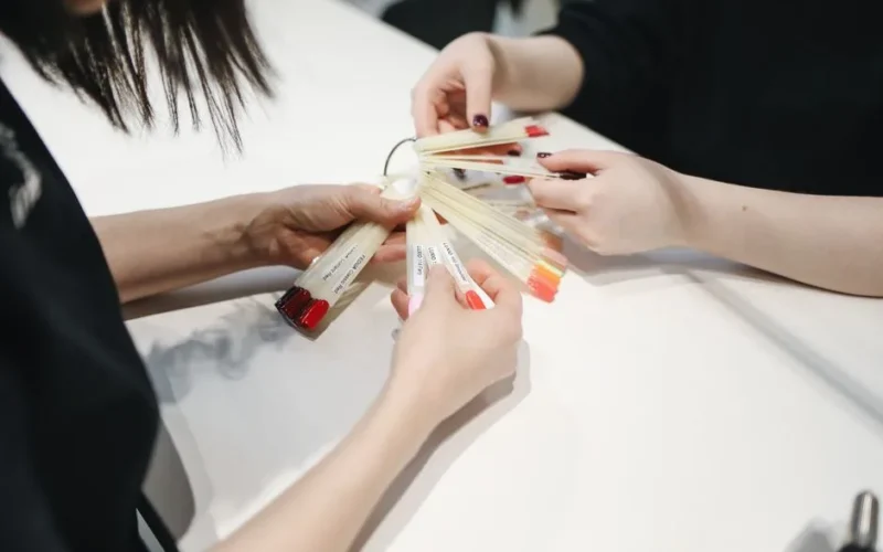 Close-up of hands selecting nail polish colors in a nail salon.