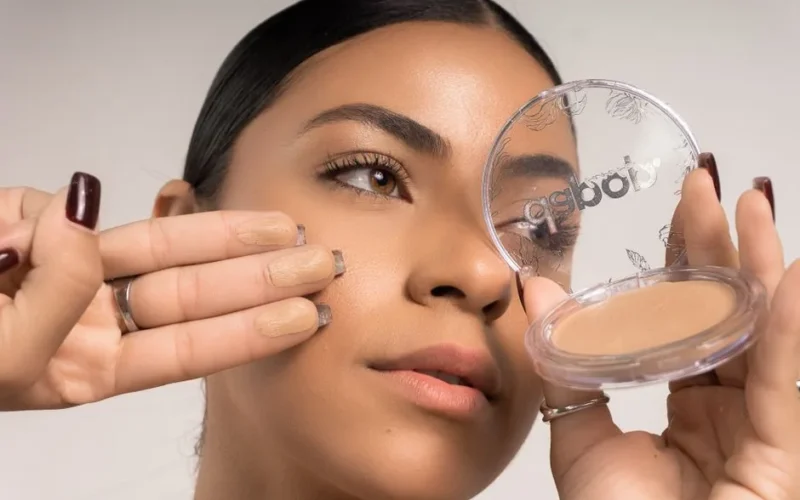 Detailed close-up of a woman applying makeup foundation using a compact.
