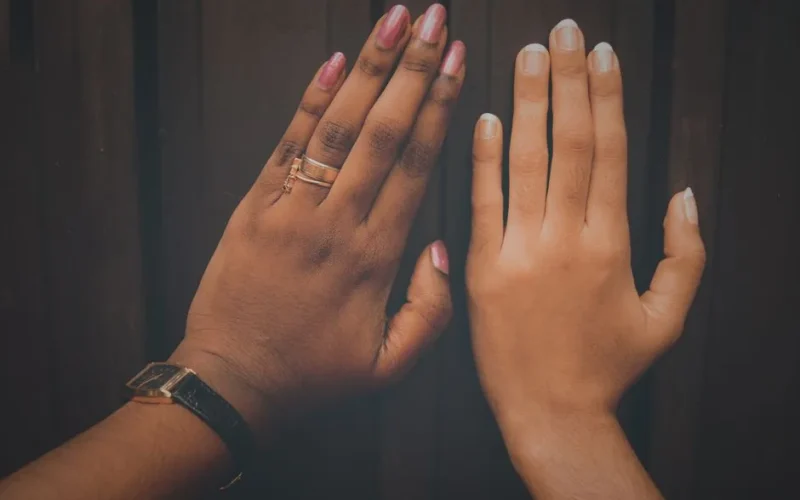 Close-up of two manicured hands with rings showcasing diversity and fashion.