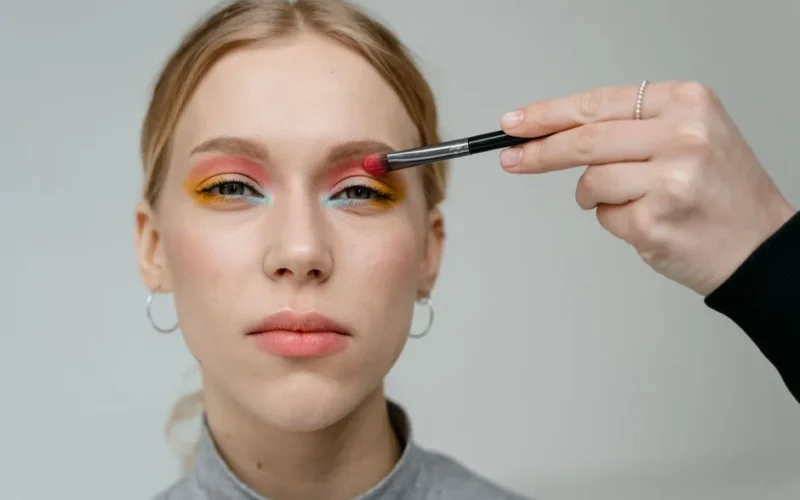 Close-up portrait of a woman with vibrant eyeshadow applied with a brush.