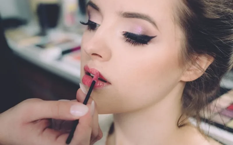 Close-up of an elegant woman having makeup applied, highlighting fashion and beauty.