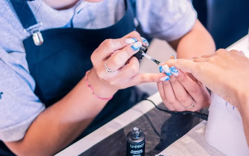 Nail artist meticulously applying nail polish in a beauty salon environment.