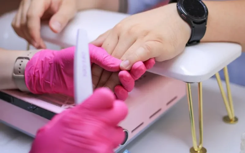 Close-up of hands receiving a manicure in a professional nail salon, highlighting attention to detail and hygiene.
