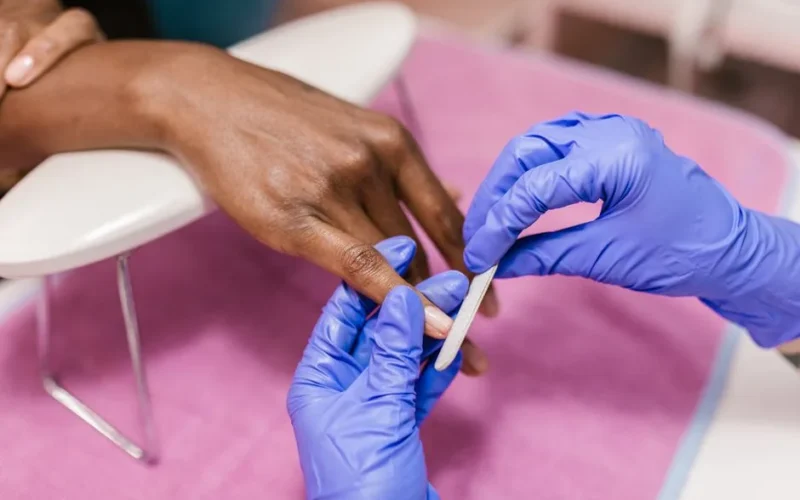 Close-up of hand receiving a manicure with latex gloves, showcasing precision and care.