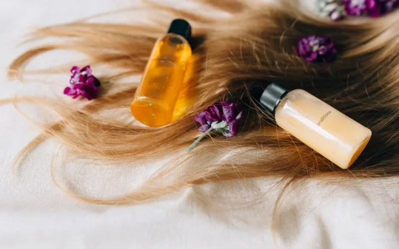 Hair care products on a bed of hair and flowers, symbolizing luxury and beauty.