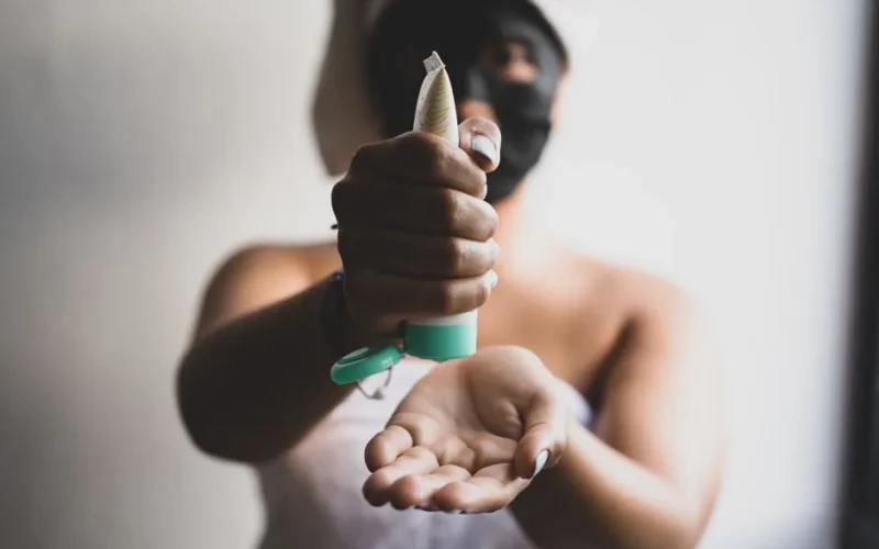 Close-up of a woman applying skincare cream with a blurred background, emphasizing a beauty routine.