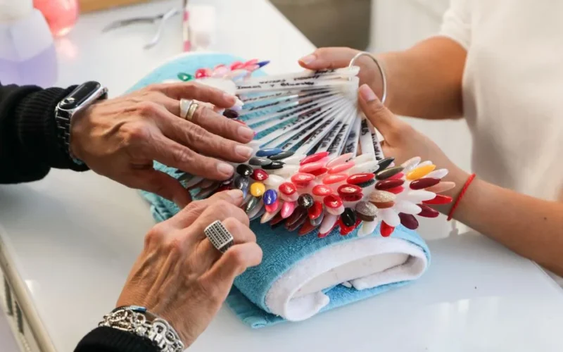 Colorful nail polish selection displayed at a salon. Hands choosing shades.