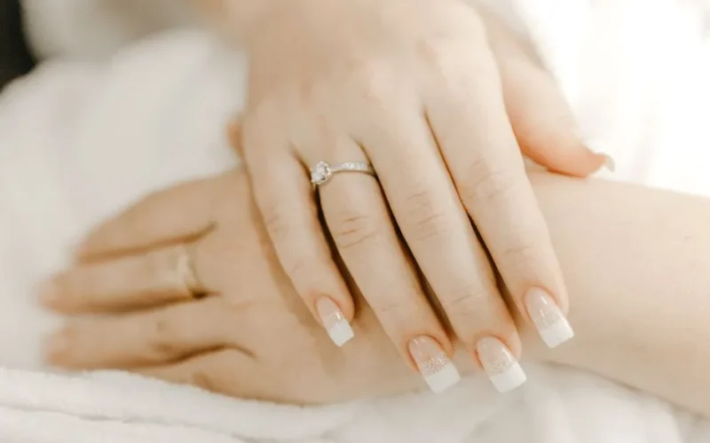 From above of hands of crop anonymous woman with classic manicure and ring with precious stone on wedding day