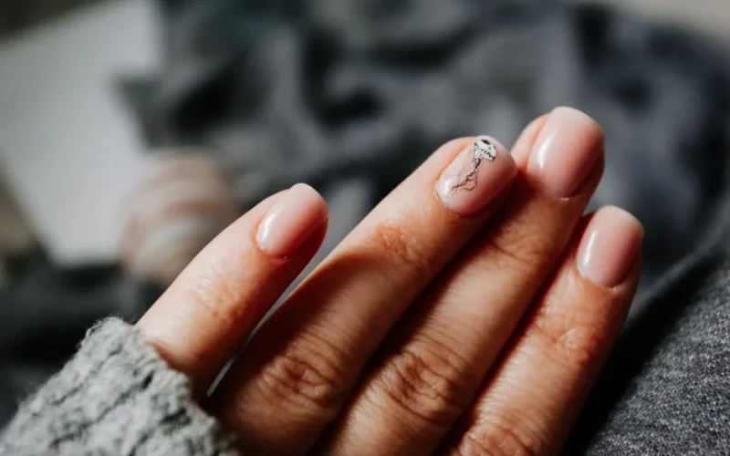 From above of crop unrecognizable female in warm sweater demonstrating hands with manicure with creative nail art