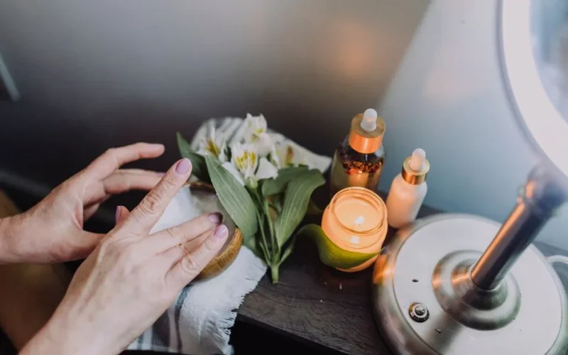 Relaxing skincare scene with hands, candles, and natural products for a soothing experience.