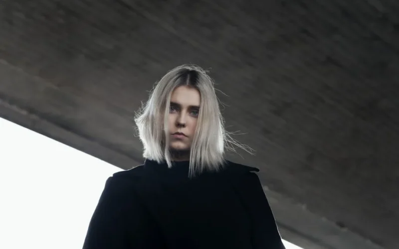 A low angle shot of a serious woman with platinum blonde hair under an urban bridge in Germany.